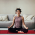 Woman meditating on a red light therapy mat for relaxation and wellness at home